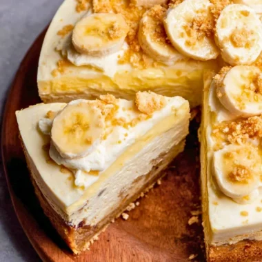 A slice of creamy Banana Pudding Cheesecake with banana slices and whipped cream on top.