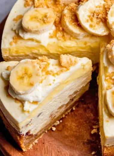 A slice of creamy Banana Pudding Cheesecake with banana slices and whipped cream on top.