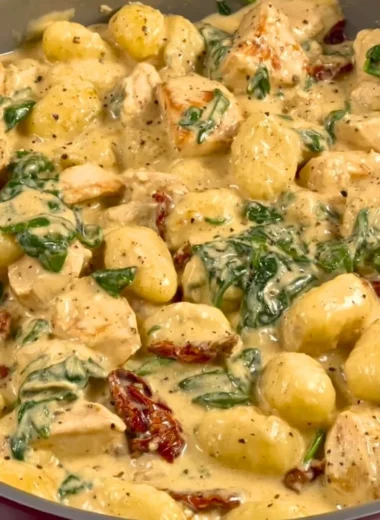 Bowl of creamy chicken gnocchi with herbs and spices on a wooden table