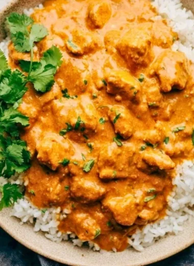 Delicious crockpot butter chicken served with rice and garnished with cilantro