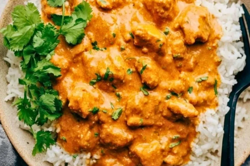 Delicious crockpot butter chicken served with rice and garnished with cilantro