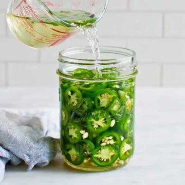 Jar of homemade pickled jalapeños with fresh ingredients