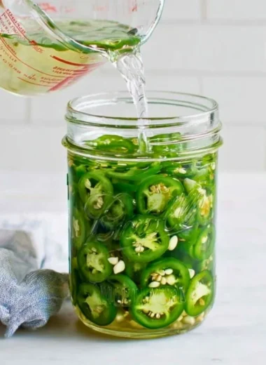 Jar of homemade pickled jalapeños with fresh ingredients