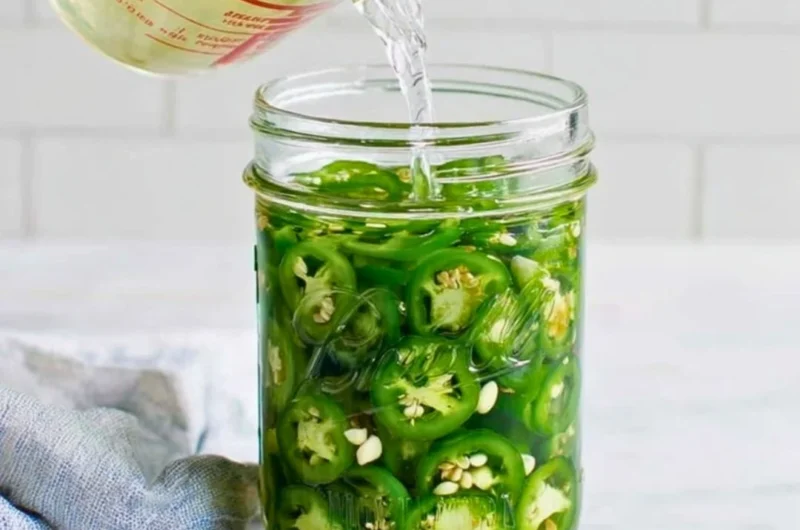 Jar of homemade pickled jalapeños with fresh ingredients