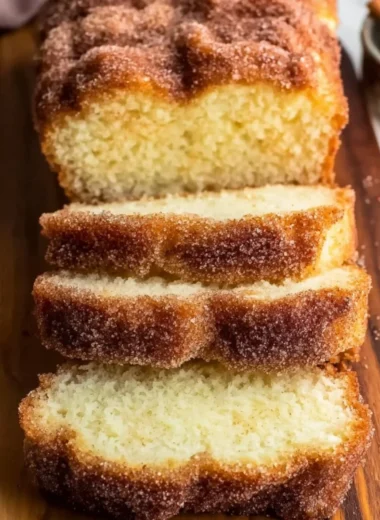 Freshly baked cinnamon sugar donut bread, sliced on a wooden board.