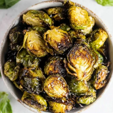 Crispy oven roasted Brussels sprouts topped with balsamic glaze on a plate.