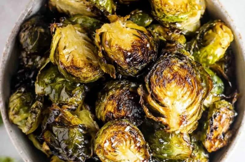 Crispy oven roasted Brussels sprouts topped with balsamic glaze on a plate.