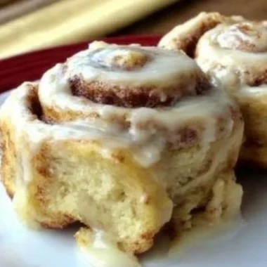 Delicious homemade cinnamon rolls topped with icing on a wooden table