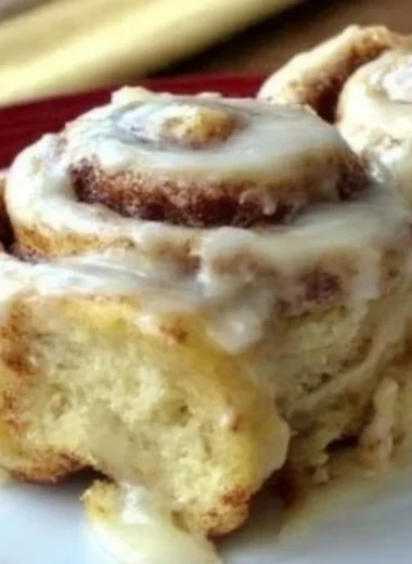 Delicious homemade cinnamon rolls topped with icing on a wooden table