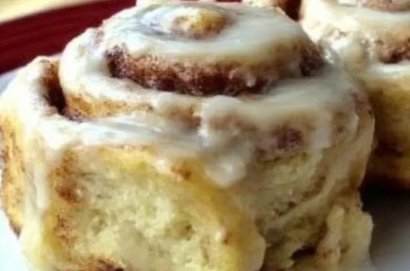Delicious homemade cinnamon rolls topped with icing on a wooden table