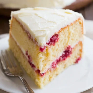 Beautiful Raspberry Lemon Cake topped with fresh raspberries and lemon slices