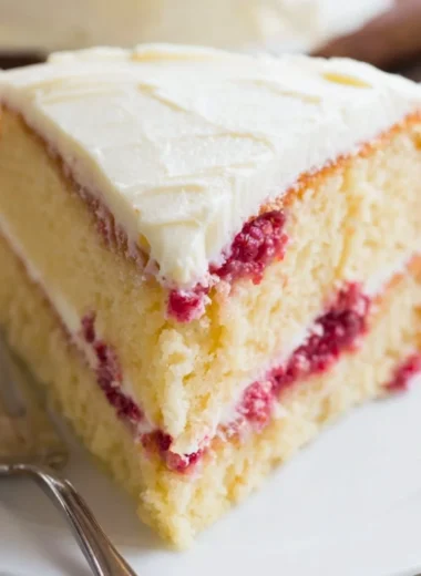 Beautiful Raspberry Lemon Cake topped with fresh raspberries and lemon slices