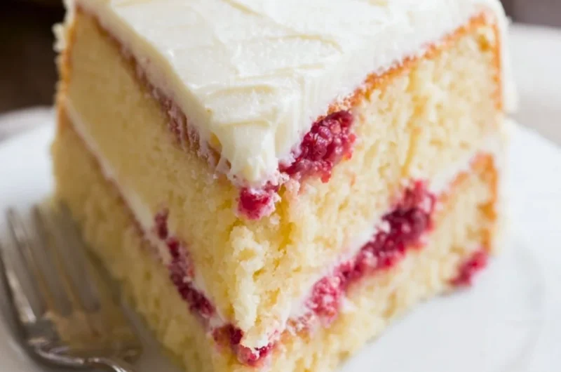 Beautiful Raspberry Lemon Cake topped with fresh raspberries and lemon slices