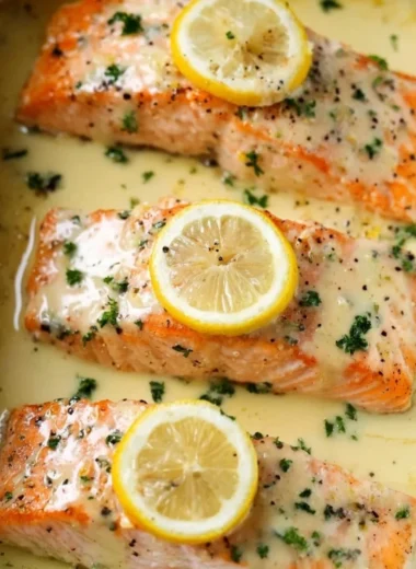 Salmon fillet topped with rich lemon cream sauce on a plate