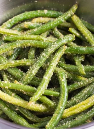A plate of crispy air fryer parmesan green beans garnished with herbs.