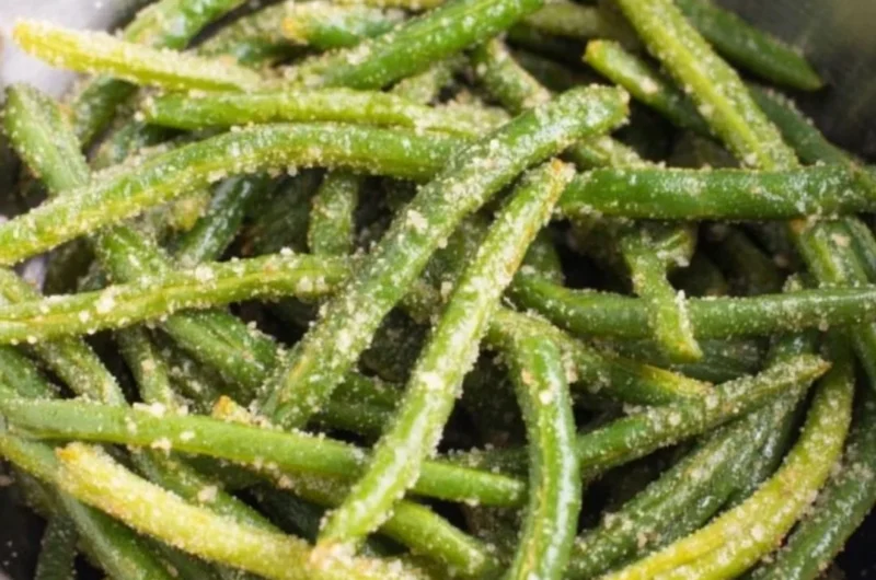 A plate of crispy air fryer parmesan green beans garnished with herbs.