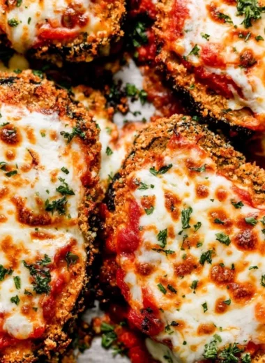 Crispy baked eggplant parmesan served with fresh herbs and marinara sauce.
