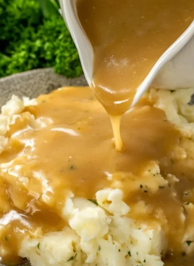 Bowl of easy homemade gravy drizzled over mashed potatoes.
