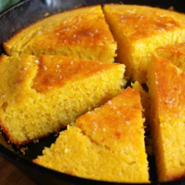 A golden slice of old-fashioned cornbread on a rustic wooden table.