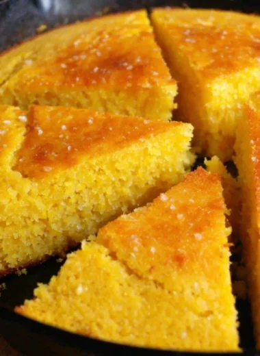 A golden slice of old-fashioned cornbread on a rustic wooden table.
