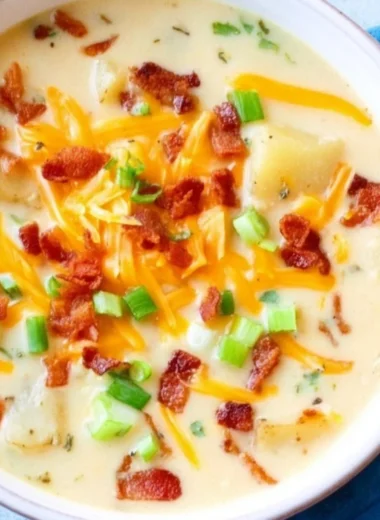 Bowl of slow cooker potato soup topped with green onions and bacon bits