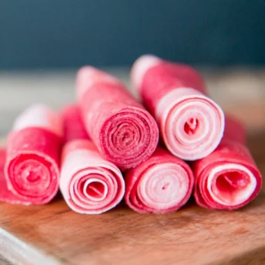 Homemade watermelon fruit leather rolled up on a wooden table